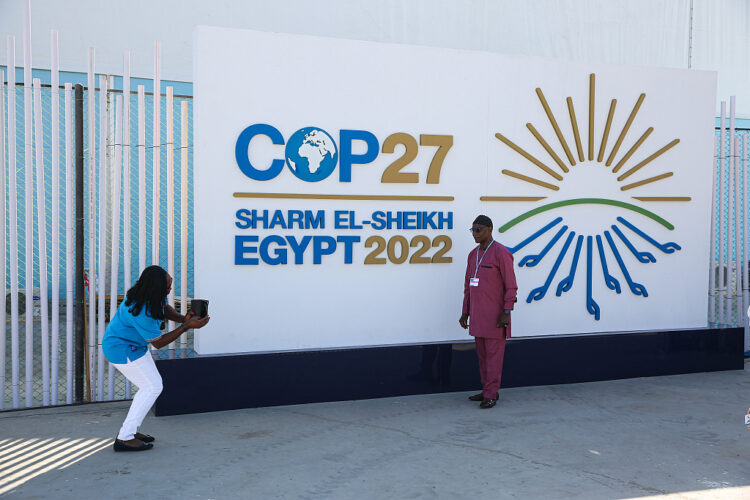 Attendees take photographs of themselves in front of a banner at the COP27 climate conference in Sharm El-Sheikh, Egypt, on Sunday, Nov. 6, 2022. Disagreements over who should pay for the harm done by climate-driven extreme weather events will be at the heart of discussions at COP27, the first to be held in Africa since 2016. Photographer: Islam Safwat/Bloomberg