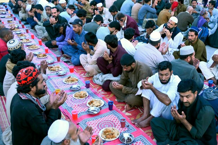 Muslim devotees pray before breaking their fast along a street during the holy month of Ramadan in Peshawar on March 27, 2023. (Photo by Abdul MAJEED / AFP) (Photo by ABDUL MAJEED/AFP via Getty Images)