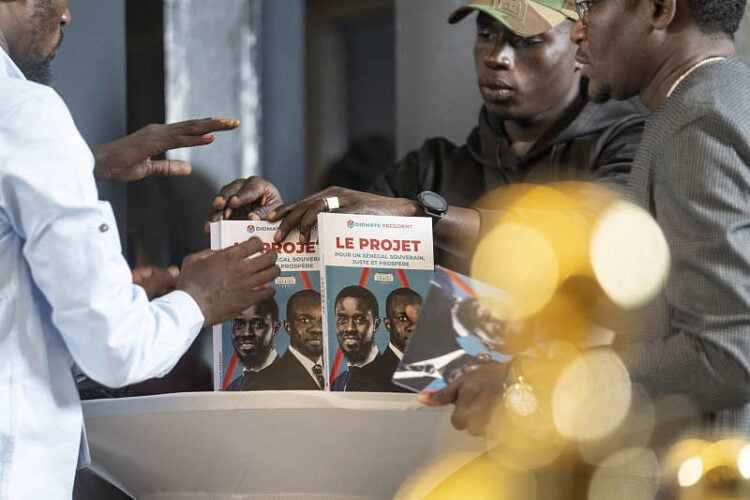 Members of Bassirou Diomaye Faye's campaign display a book called "The Project" as he holds a press conference after winning the presidential elections in Dakar, Senegal, on Monday, March 25, 2024. (AP Photo/Mosa'ab Elshamy)