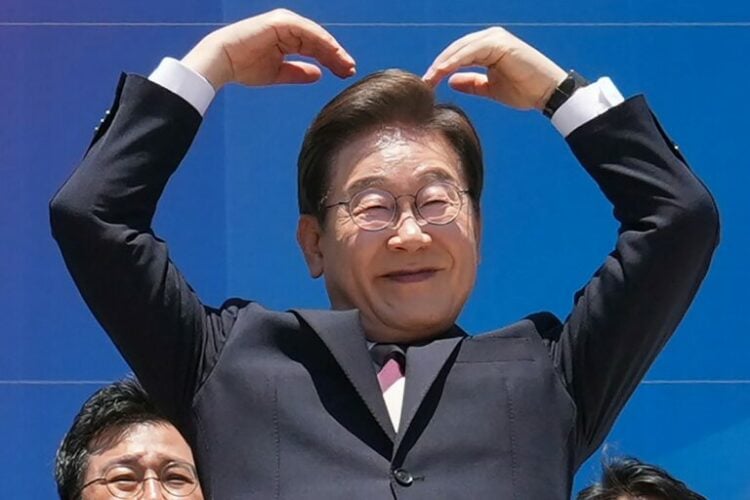South Korea's President Lee Jae-myung makes an arm heart gesture to the people outside the National Assembly as he leaves following the inauguration ceremony in Seoul on June 4, 2025. (Photo by Lee Jin-man / POOL / AFP)